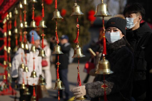 Женщина прикасается к колокольчикам, чтобы привлечь удачу, пока люди собираются на ярмарке в храме Дитань в первый день китайского лунного Нового года в Пекине в среду, 29 января 2025 года. - Sputnik Беларусь