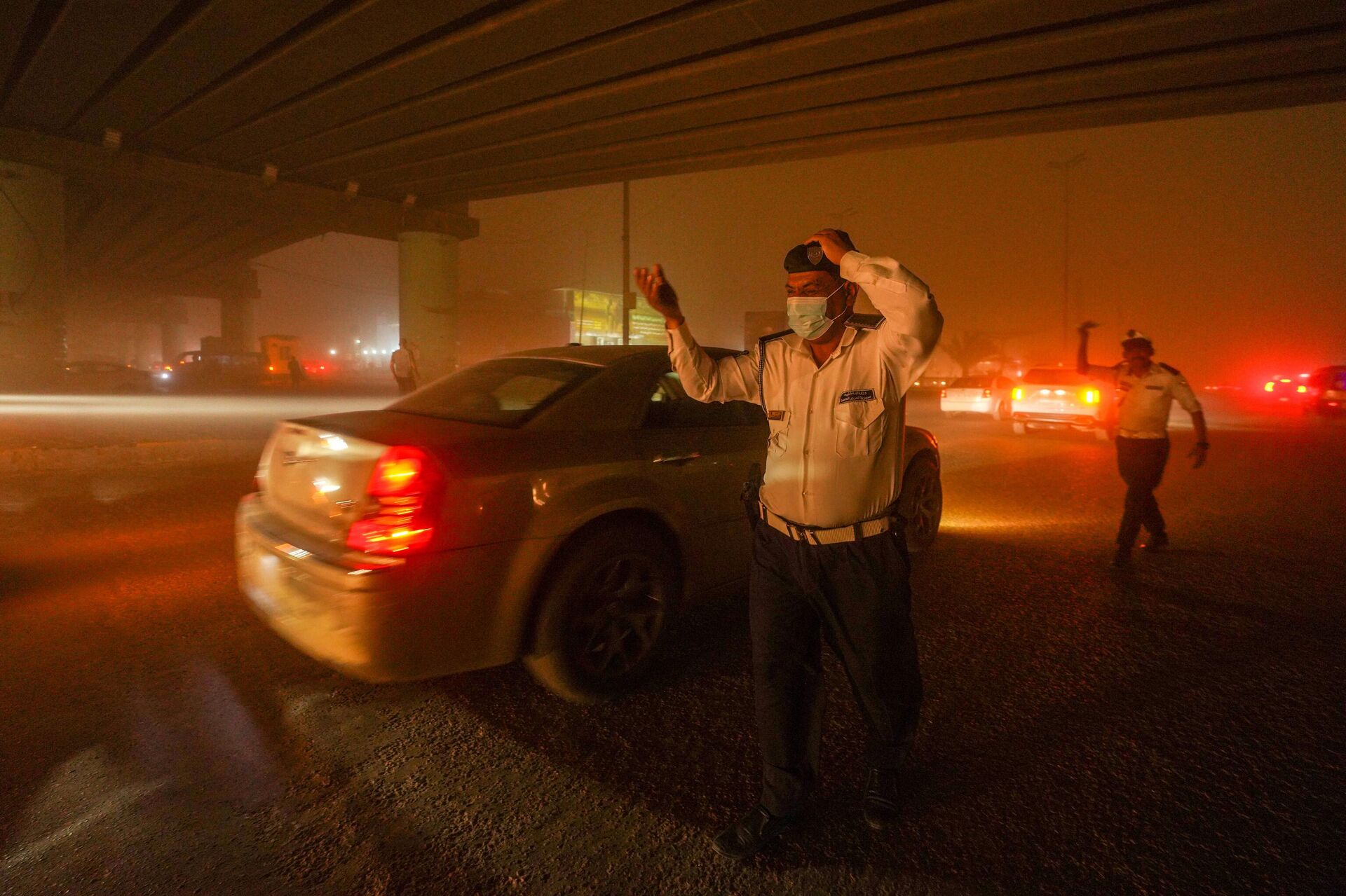 Полицейский в защитной маске на дороге во время песчаной бури - Sputnik Беларусь, 1920, 15.04.2025