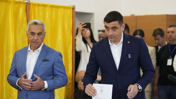Кандидат в президенты Джеордже Симион (справа) голосует рядом с Кэлином Джорджеску, победителем первого тура аннулированных выборов прошлого года - Sputnik Беларусь