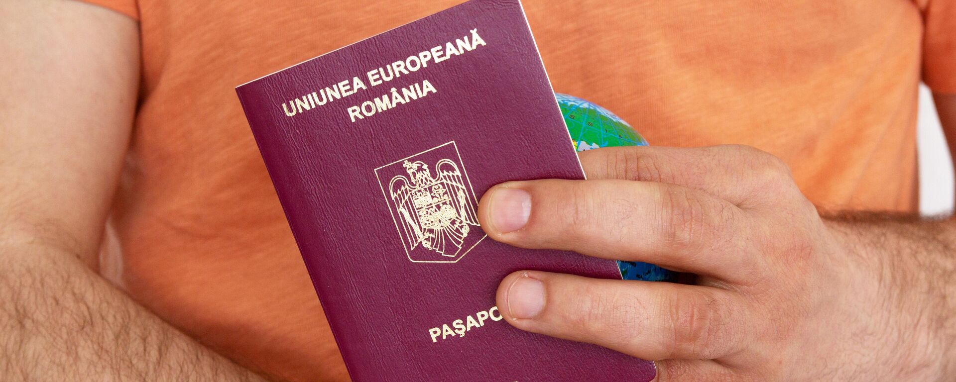 Мужчина держит в руках румынский паспорт - Sputnik Беларусь, 1920, 20.05.2025