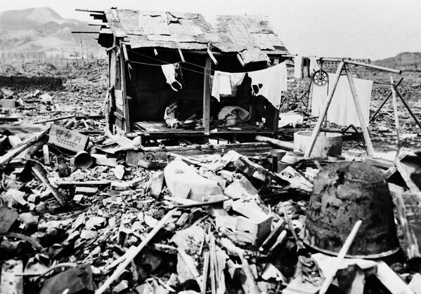 Японская семья ест рис в грубой хижине, которую они построили из обломков, оставшихся на месте, где когда-то стоял их дом, в Нагасаки, 14 сентября 1945 года - Sputnik Беларусь