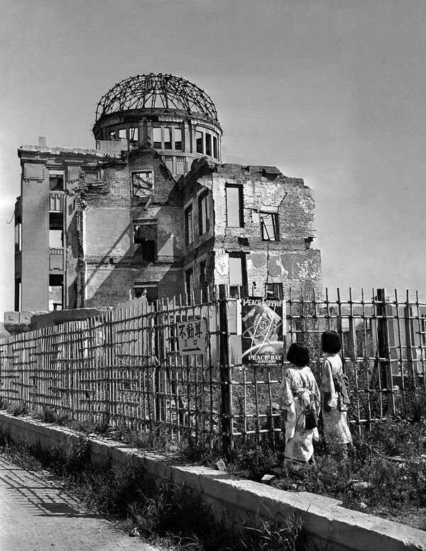 5 жніўня 1949 года. Дзеці глядзяць на плакат побач з месцам падзення бомбы ў Хірасіме, Японія. На заднім плане – агароджаны бамбукавым плотам Выставачны цэнтр Гандлёва-прамысловай палаты Хірасімы, будынак быў пабудаваны ў 1915 годзе чэшскім архітэктарам Янам Летцэлем.Будынак знаходзіўся ўсяго за 160 м ад эпіцэнтра выбуху, аднак уцалеў. Загінулі ўсе, хто быў унутры. Пасля вайны яго захавалі як памяць аб ахвярах бамбардзіроўкі. Цяпер тут музей "Атамны Купал" – купал будынка першапачаткова быў з медзі, якая аплавілася ў момант выбуху, пакінуўшы голы каркас. 5 жніўня 1949 года. Дзеці глядзяць на плакат побач з месцам падзення бомбы ў Хірасіме, Японія. На заднім плане – агароджаны бамбукавым плотам Выставачны цэнтр Гандлёва-прамысловай палаты Хірасімы, будынак быў пабудаваны ў 1915 годзе чэшскім архітэктарам Янам Летцэлем.Будынак знаходзіўся ўсяго за 160 м ад эпіцэнтра выбуху, аднак уцалеў. Загінулі ўсе, хто быў унутры. Пасля вайны яго захавалі як памяць аб ахвярах бамбардзіроўкі. Цяпер тут музей "Атамны Купал" – купал будынка першапачаткова быў з медзі, якая аплавілася ў момант выбуху, пакінуўшы голы каркас. - Sputnik Беларусь