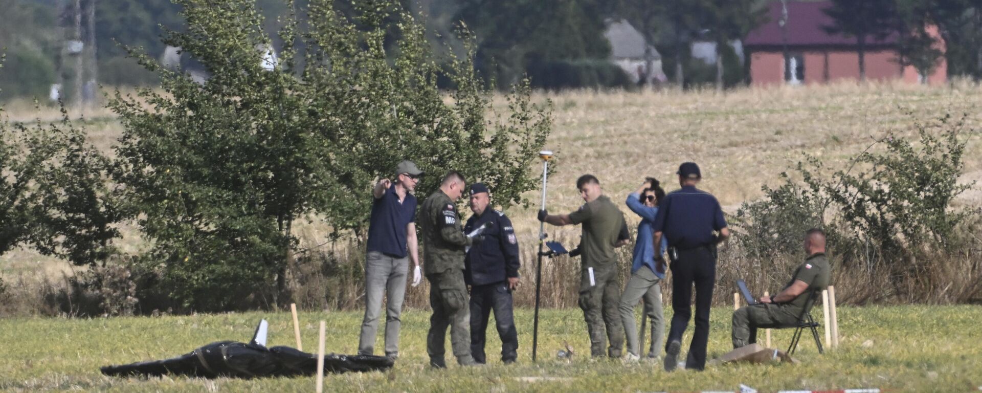 Полиция и военная полиция забирают части поврежденного БПЛА, сбитого польскими властями на месте происшествия в Вогине, Польша - Sputnik Беларусь, 1920, 14.09.2025