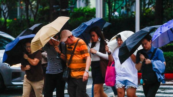 Kюди с зонтиками во время супертайфуна Рагаса на Филиппинах - Sputnik Беларусь
