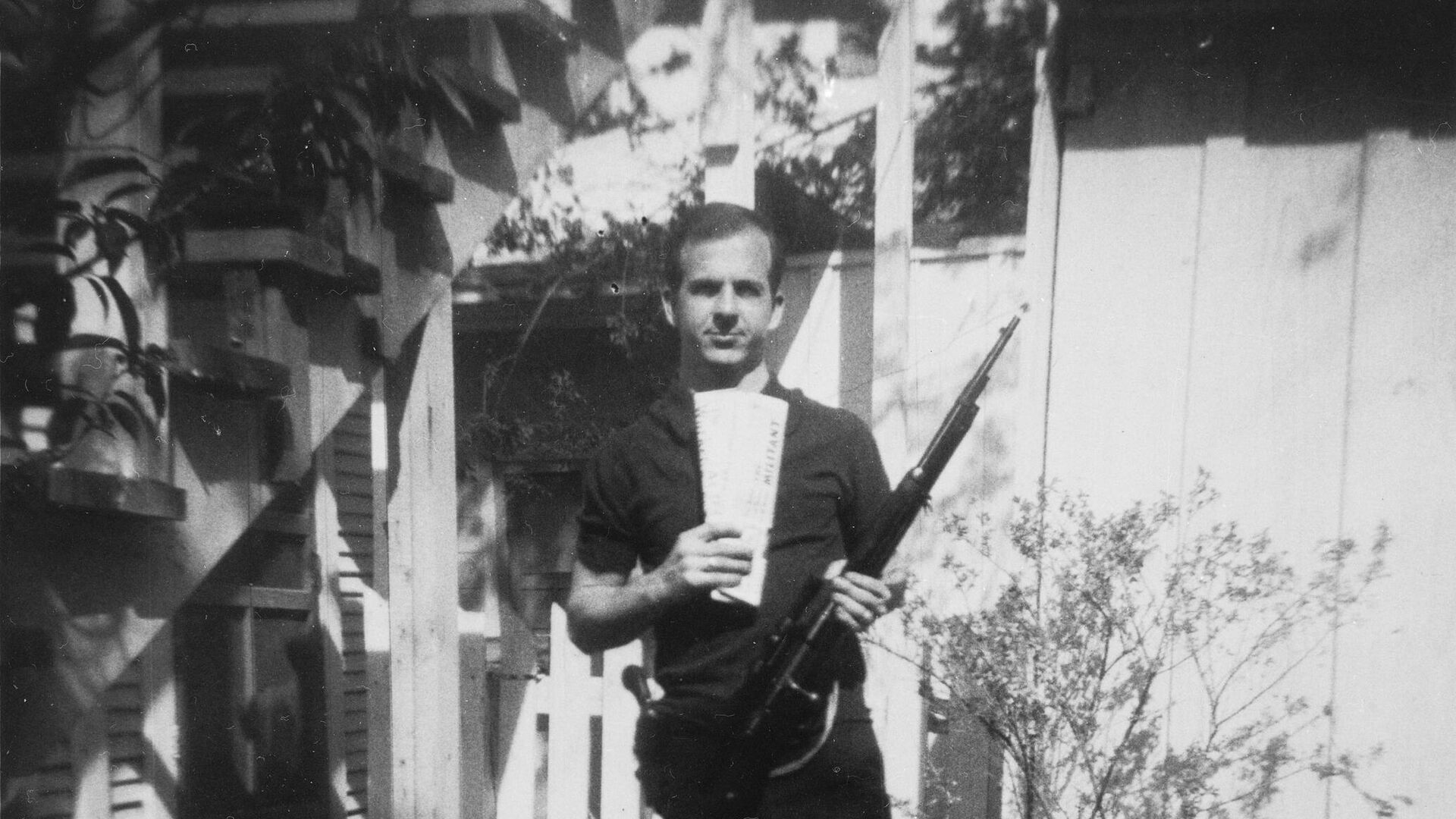 Ли Харви Освальд с винтовкой на заднем дворе дома в Техасе, США
