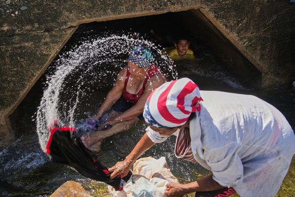 Люди стирают одежду в реке, пострадавшей от урагана "Мелисса", прошедшего через южное побережье города Сантьяго-де-Куба на Кубе.