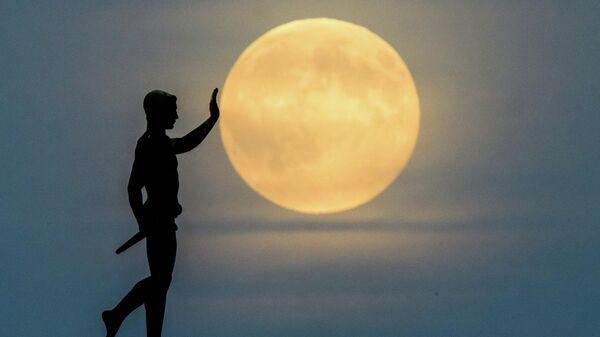 Луна восходит на горизонте за статуей Факелоносец (1937) на северном берегу озера Маш, Германия - Sputnik Беларусь