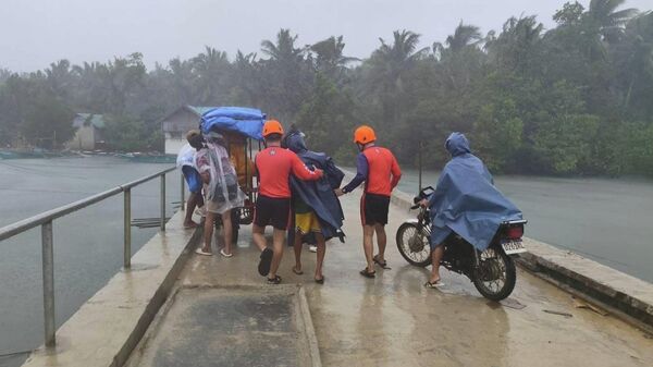 Спасатели эвакуируют людей в безопасные места в провинции Кесон на востоке Филиппин в преддверии тайфуна Фунг-вонг 9 ноября 2025 года - Sputnik Беларусь