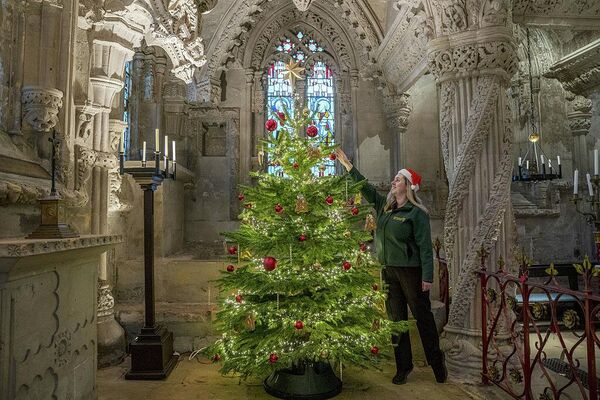 Экскурсовод Меган Кингхорн украшает рождественскую елку в Рослинской часовне в Шотландии. Часовня, основанная в 1446 году и показанная в фильме "Код да Винчи", открыта для посетителей весь праздничный сезон и проводит специальные службы и концерты на Рождество. - Sputnik Беларусь