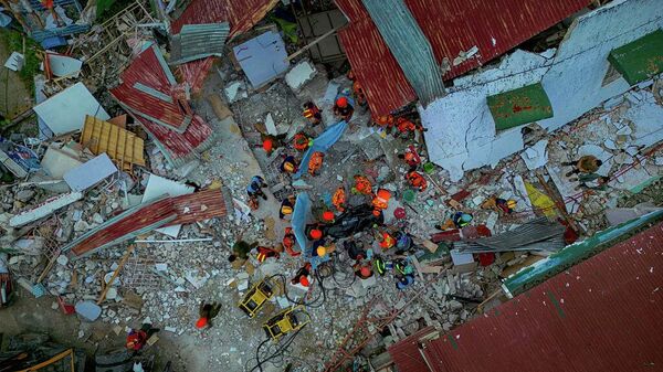 На аэрофотоснимке спасатели несут тело местого жителя, извлеченное из-под обломков рухнувшего жилого дома 1 октября 2025 года в городе Бого, провинция Себу, Филиппины.  - Sputnik Беларусь