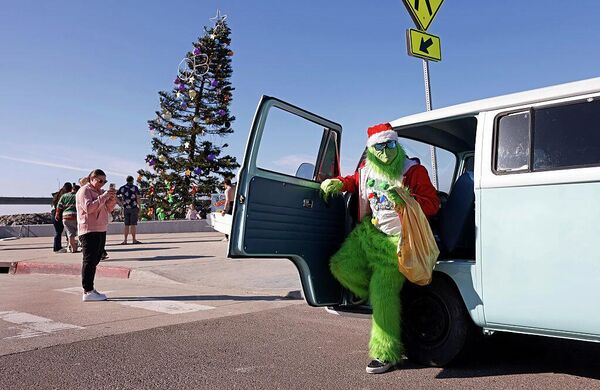 Мужчина в костюме Гринча перед началом рождественского празднования на Оушен-Бич в Сан-Диего, Калифорния.