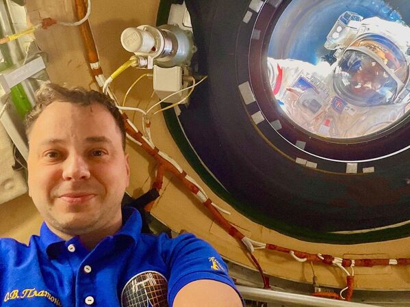 Космонавт Олег Платонов делает селфи на борту МКС, в то время как его коллеги Алексей Зубрицкий и Сергей Рыжиков работают снаружи