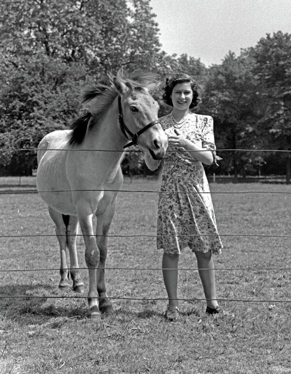 Принцесса Елизавета (будущая королева Великобритании Елизавета II) с лошадью в саду Виндзорского замка, Беркшир, Великобритания, 30 мая 1944 года. - Sputnik Беларусь