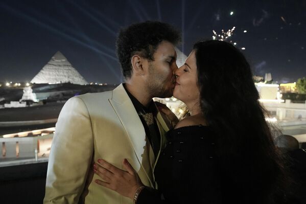 Немецкие туристы целуются на фоне новогоднего фейерверка над пирамидами Гизы, на окраине Каира.