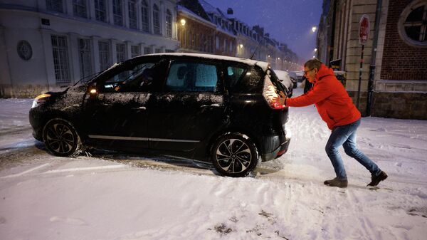 Мужчина толкает свой автомобиль во время снегопада , в Лилле, на севере Франции - Sputnik Беларусь