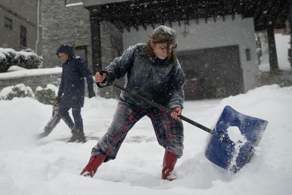 Жители города Цинциннати в Огайо расчищают снег возле своего дома.