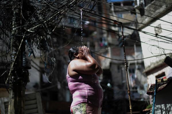 Келли Кристина да Круз охлаждается в общественном душе в фавеле Росинья в страдающем от изнурительной жары Рио-де-Жанейро, январь 2026 года. - Sputnik Беларусь