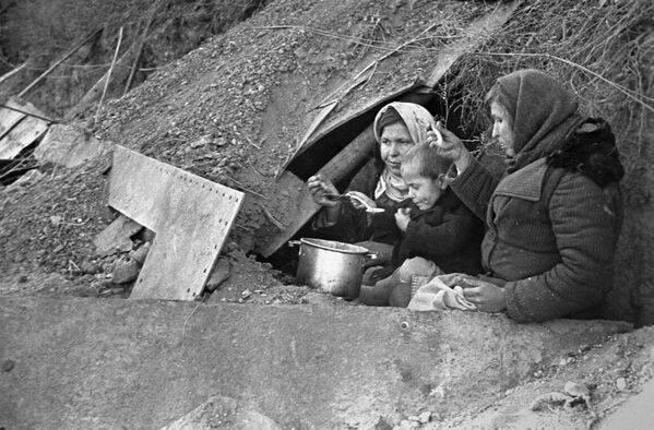Жыхары горада, якія засталіся без прытулку, ля ўвахода ў зямлянку, прыстасаваную пад жыллё. - Sputnik Беларусь