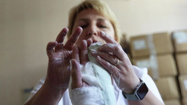 Медицинский работник накладывает гипс на руку пациента - Sputnik Беларусь