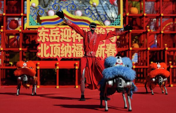 Робот-гуманоид исполняет танец с роботами-собаками в костюмах львов в первый день лунного Нового года Лошади в храме Няннян в Пекине.