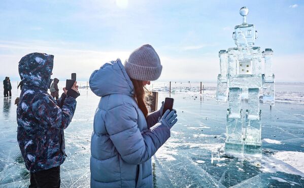 Участники XII Зимнего фестиваля ледового искусства "Живи на Байкале" 2026 у скульптуры в виде робота. - Sputnik Беларусь