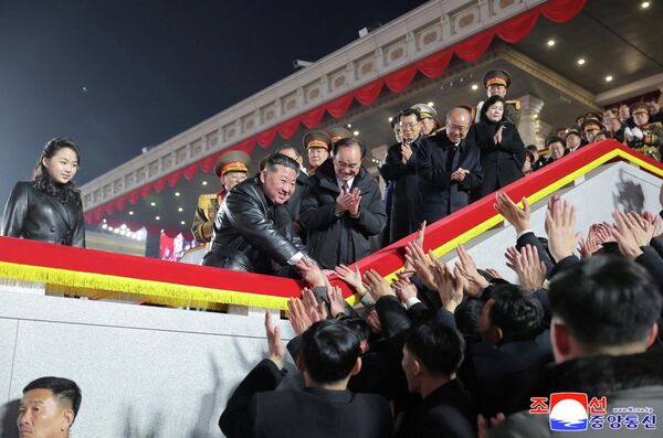 Лидер Северной Кореи Ким Чен Ын вместе с дочерью приветствует собравшихся на военном параде в честь IX съезда Трудовой партии Кореи в Пхеньяне.