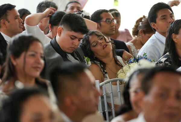 Женщина спит рядом со своим женихом перед массовой свадьбой в честь Дня святого Валентина в Лиме, ​​Перу.