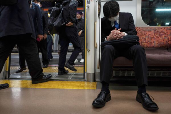 Пассажир спит в метро Токио.