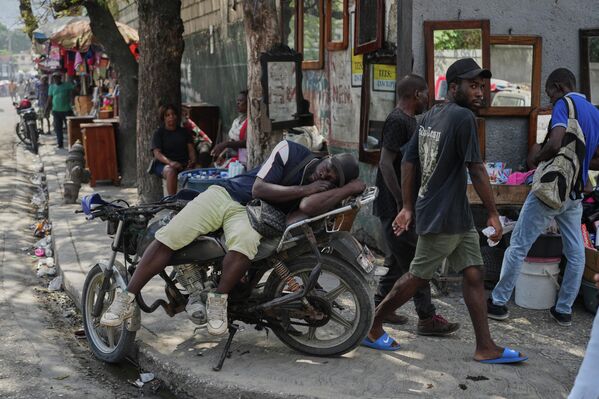 Водитель мототакси заснул на своем мотоцикле, ожидая клиентов в Порт-о-Пренсе на Гаити.