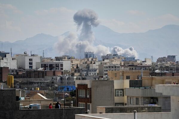 Людзі назіраюць з даху, як пасля ўдару ў Тэгеране ўздымаецца слуп дыму. - Sputnik Беларусь