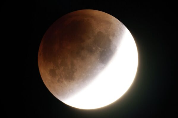 Полная Луна Червя светится оранжевым цветом, приближаясь к полному затмению - кадр снят из города Москоу в штате Айдахо.