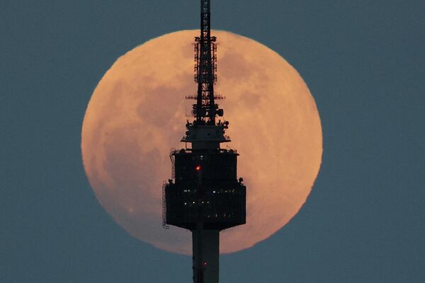 Полная луна восходит за телебашней в Сеуле, Южная Корея.