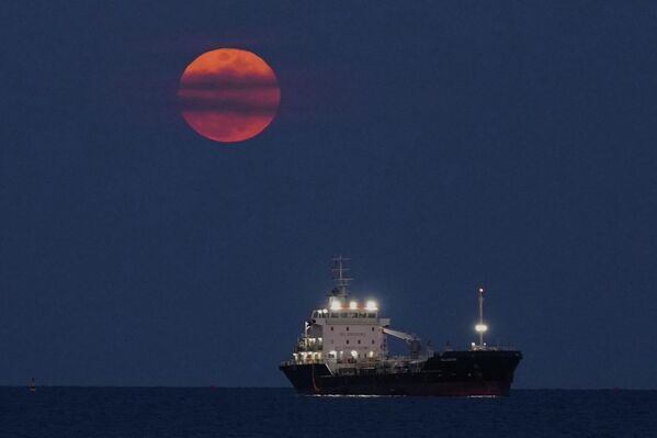 Кровавая луна восходит над Средиземным морем на фоне стоящего на якоре корабля в Лимассоле, Кипр.