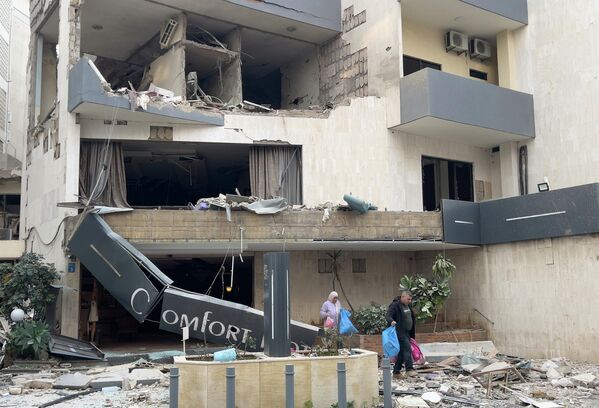 Постояльцы покидают поврежденный отель, пострадавший от израильского авиаудара в Хазмие, к востоку от Бейрута.