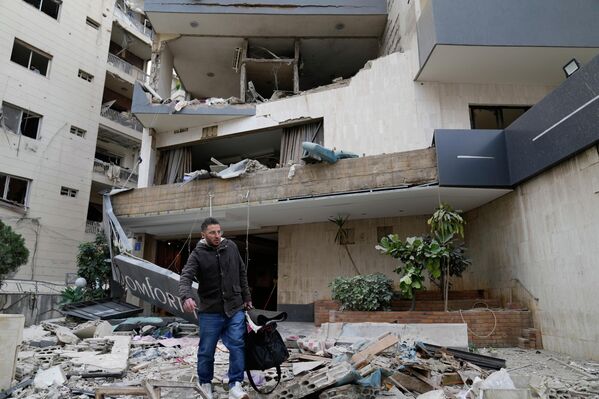Мужчина с вещами покидает поврежденный израильским авиаударом отель в Хазмие, к востоку от Бейрута, Ливан.