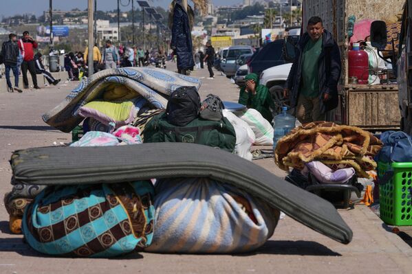 Беженцы, спасающиеся от израильских авиаударов на юге Ливана, сидят со своими вещами на набережной в южном портовом городе Сидон, Ливан.