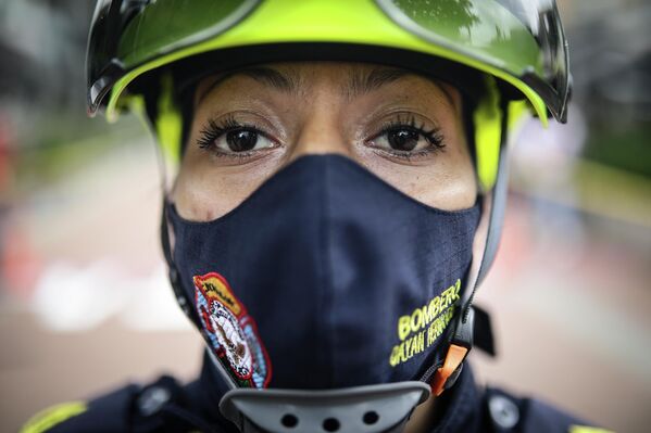 Женщина-пожарный участвует в полосе препятствий вместе со своими коллегами-мужчинами на соревнованиях в Боготе, Колумбия (ноябрь 2021 года).