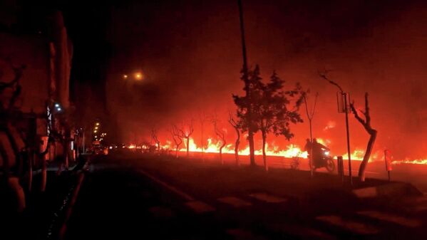 Мотоцикл проезжает мимо горящего бульвара Кохсар в Тегеране после авиаударов США и Израиля по Ирану (10 марта 2026 года).