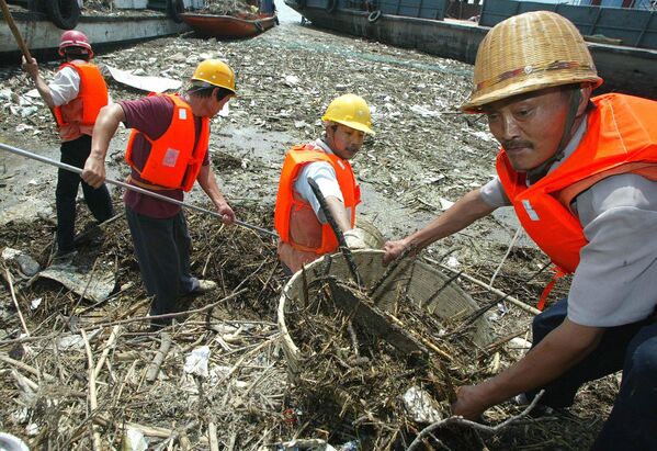 Рабочие собирают плавающий мусор из воды рядом со шлюзами плотины "Три ущелья" на реке Янцзы в Китае.Река Янцзы опасна катастрофическими наводнениями, возникающими из-за проливных дождей, а также экстремальным уровнем загрязнения промышленными и бытовыми отходами. - Sputnik Беларусь