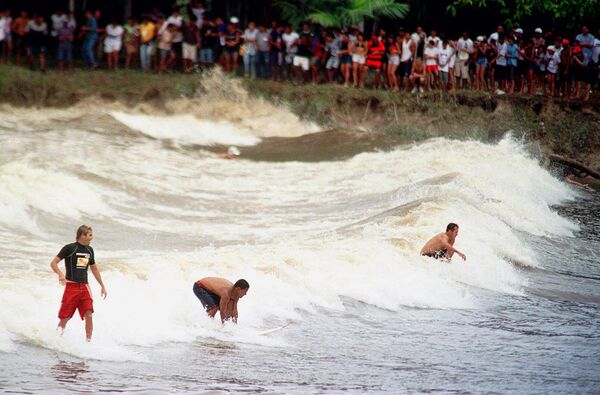 Серферы покоряют волну "Поророка" на реке Амазонке.  Волна "Поророка" — это мощная приливная волна (бор), возникающая в устье Амазонки, когда вода Атлантического океана входит в реку, заставляя ее течь вспять. Волна высотой 3–7 метров движется против течения со скоростью до 40 км/ч, преодолевая до 800 км вглубь суши. Это опасное, но популярное у экстремалов явление, часто называют "гремящей водой". - Sputnik Беларусь
