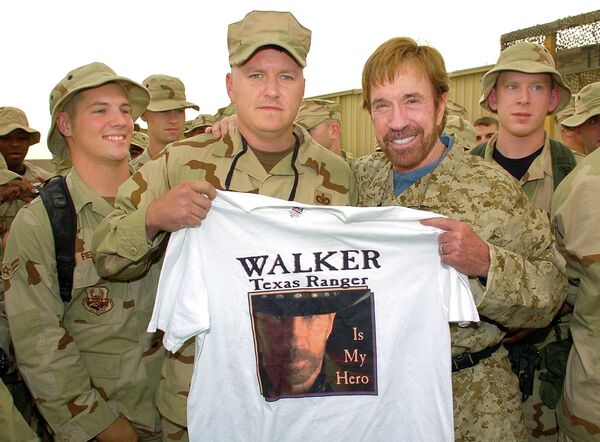 Актер и мастер боевых искусств Чак Норрис (справа) во время встречи с американскими военнослужащими на авиабазе Али-аль-Салим в Кувейте в октябре 2006 года.