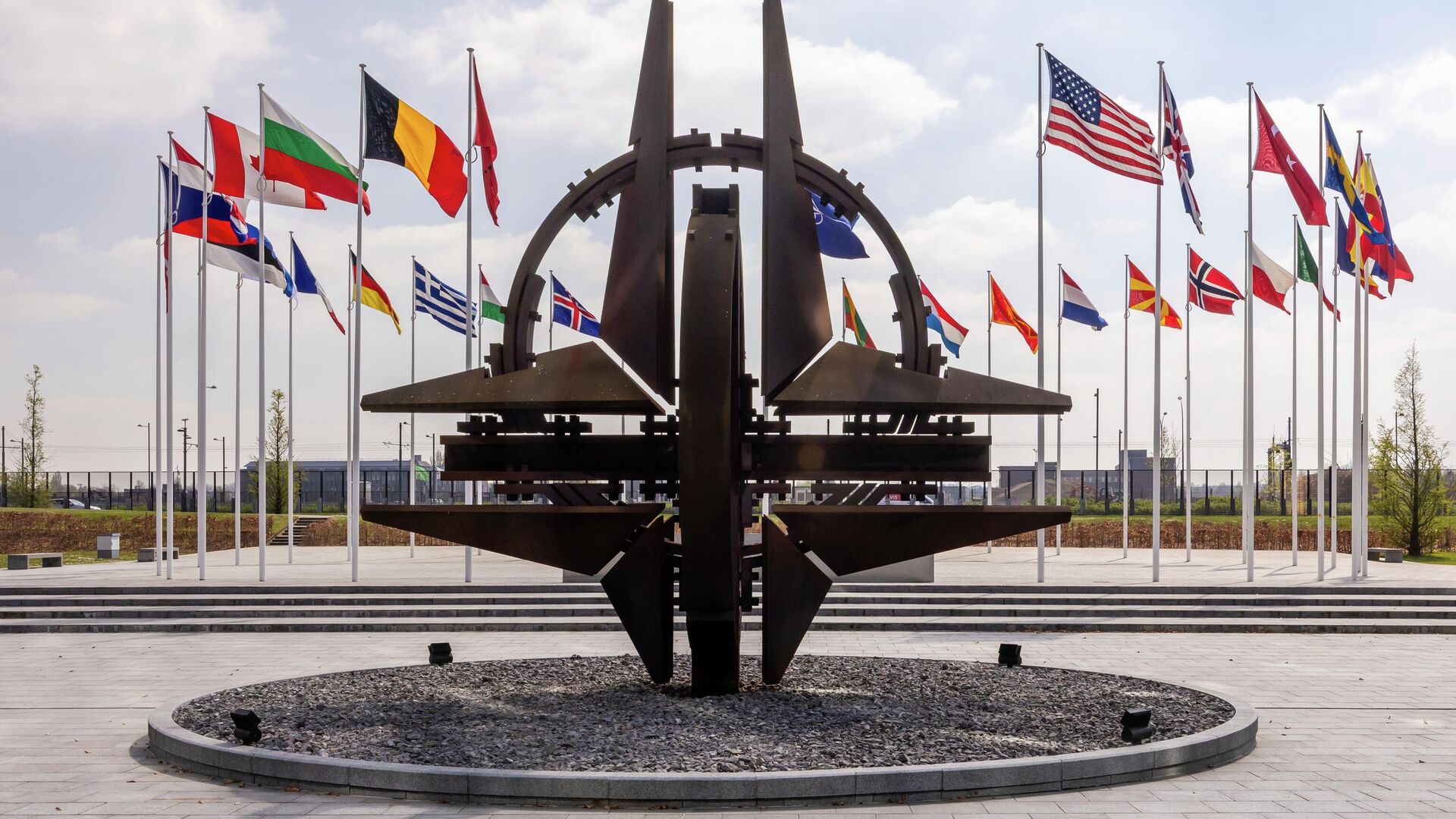 Флаги стран-участниц НАТО и эмблема альянса перед штаб-квартирой  НАТО в Брюсселе - Sputnik Беларусь, 1920, 04.04.2026