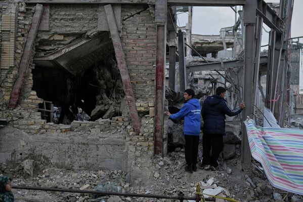 Мужчины осматривают разрушенное здание в комплексе Гранд-Хоссейния в Зенджане. - Sputnik Беларусь