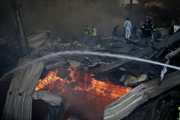 Пожарные пытаются потушить пламя на месте израильского авиаудара по многоквартирному дому в Бейруте.