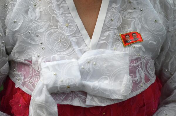 Значок с портретами Ким Чен Ира и Ким Ир Сена на одежде жительницы Пхеньяна. - Sputnik Беларусь