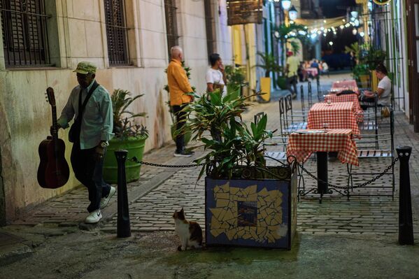 Уличный музыкант проходит мимо ресторана в Гаване. - Sputnik Беларусь