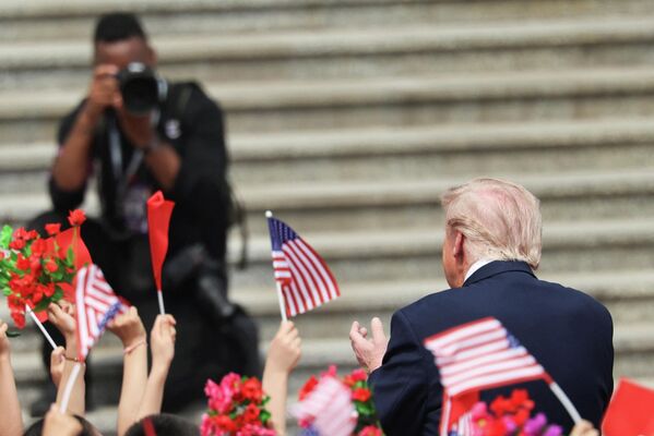 Дети с китайскими и американскими флажками приветствуют президента США Дональда Трампа.
