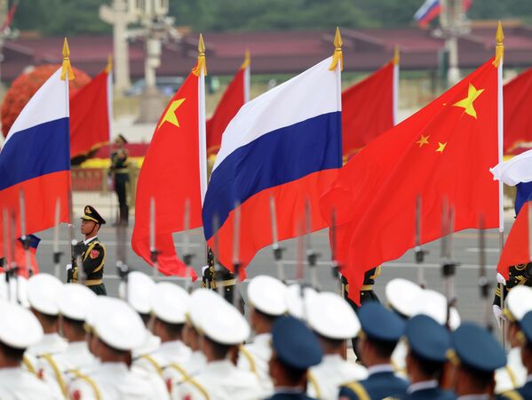 Ганаровая варта Народна-вызваленчай арміі Кітая трымае кітайскія і расійскія флагі перад цырымоніяй прывітання прэзідэнта Расіі. - Sputnik Беларусь