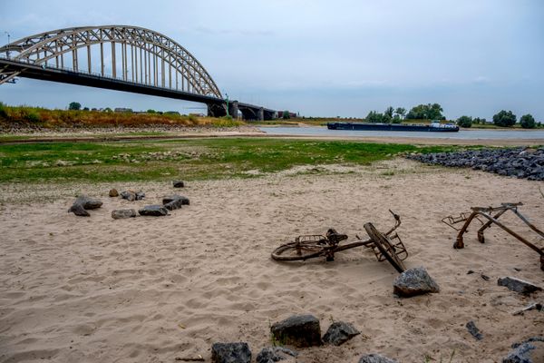 Ржавый велосипед и тележка для покупок видны на фоне спада уровня воды из-за засухи в реке Слинге в Варссевельде в Нидерландах.