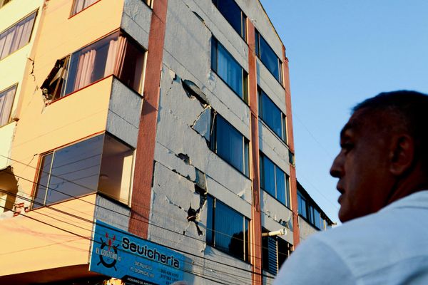 Мужчина стоит перед зданием, поврежденным землетрясением, в Манисалесе. - Sputnik Беларусь